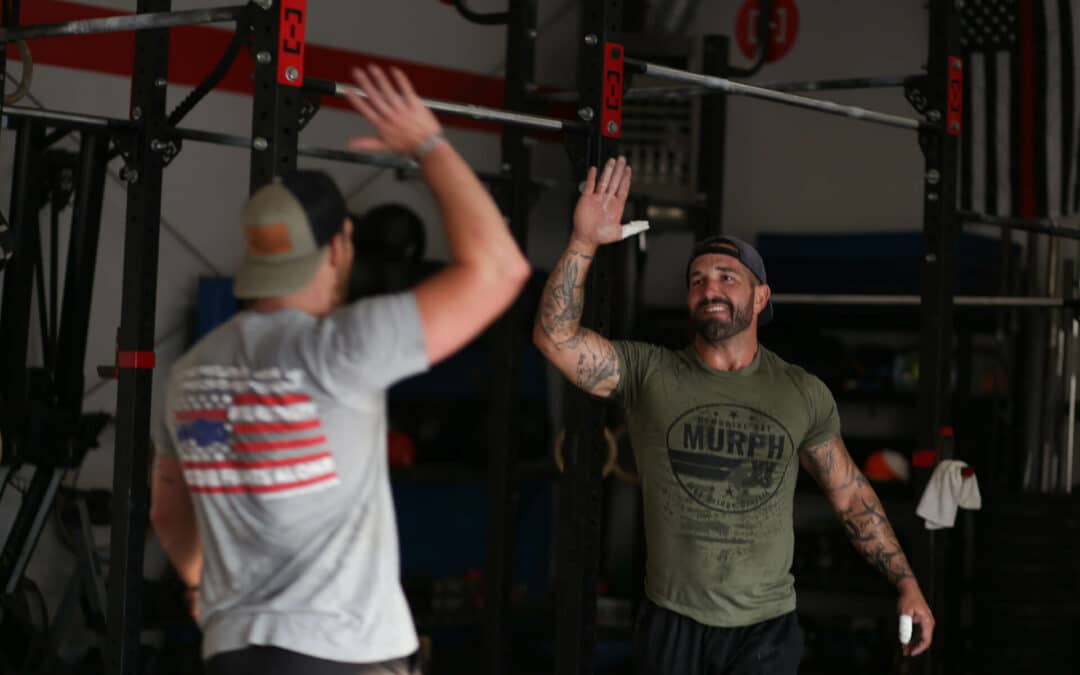 Two veterans celebrating with a high five in a WarriorWOD fitness session.