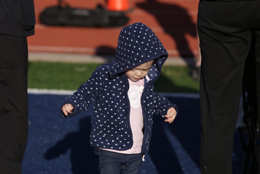 Toddler in a navy fleece walking the Kids Fun Run on the field at the Hustle for Heroes 5K