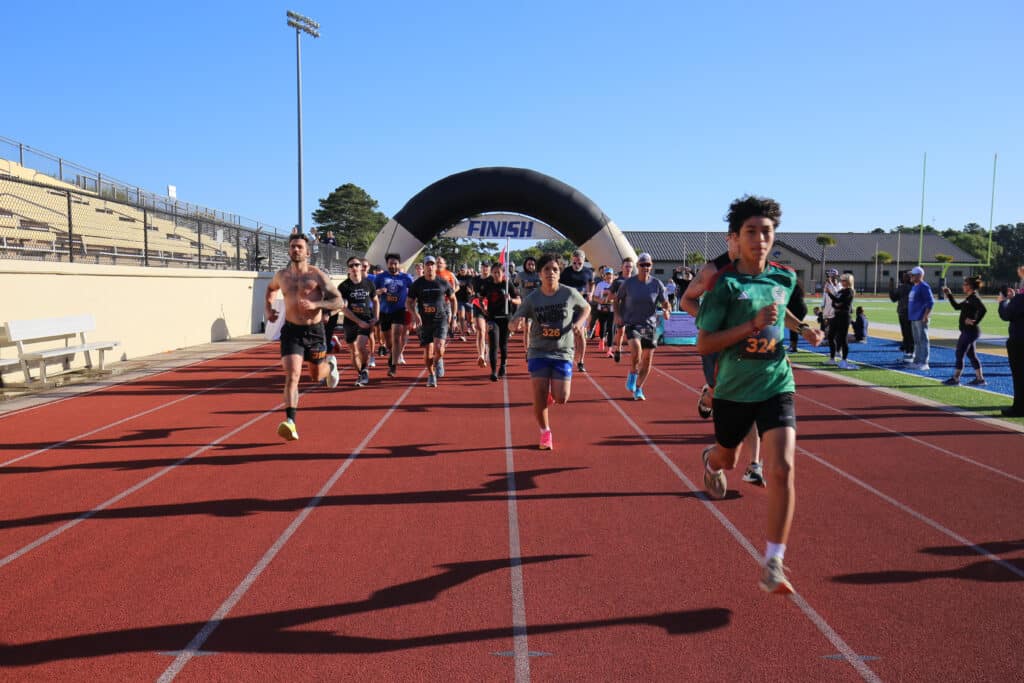 A young runner leads the Hustle for Heroes 5K field away from the start on the track at Charleston Southern University