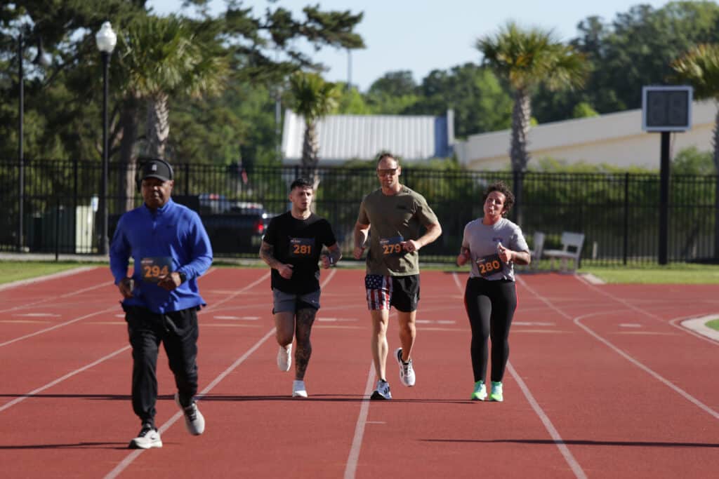 Four Hustle for Heroes 5K participants running and walking side by side on the track at Charleston Southern University