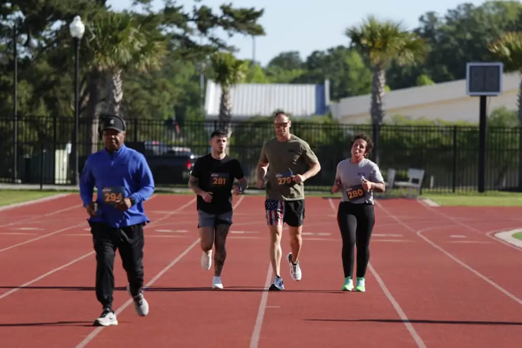 Four Hustle for Heroes 5K participants running and walking side by side on the track at Charleston Southern University