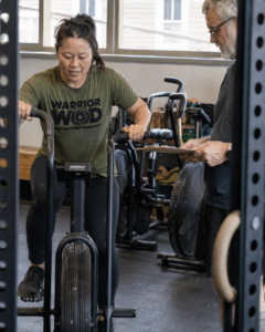 Veteran in WarriorWOD PTSD recovery program training on air bike with coach during Warrior Class